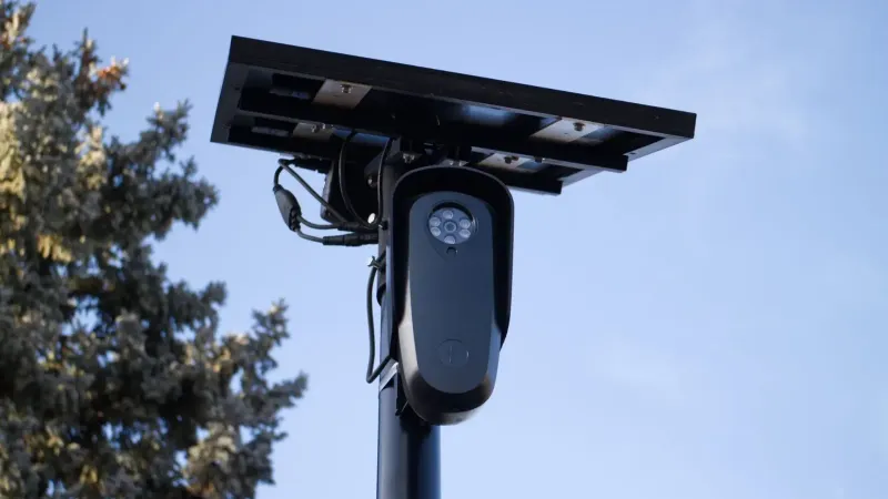 A solar-powered outdoor surveillance camera mounted on a pole, capturing clear day images.