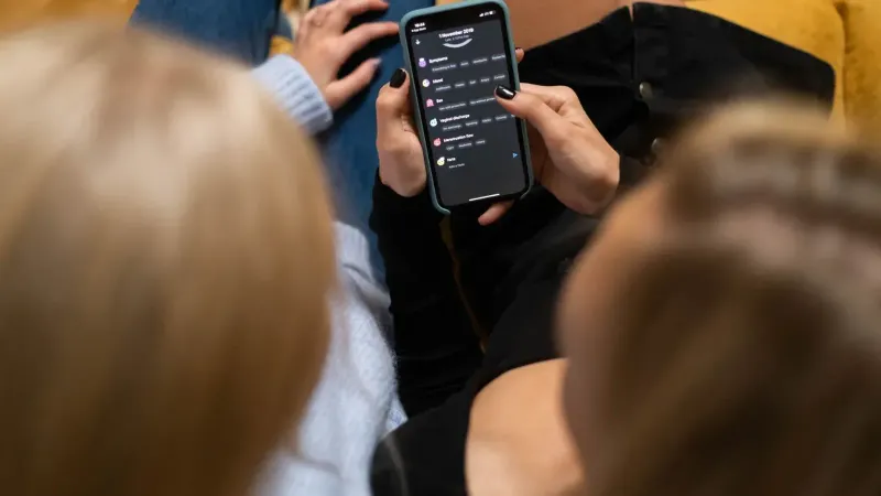 Two women browsing social media together on a smartphone indoors.