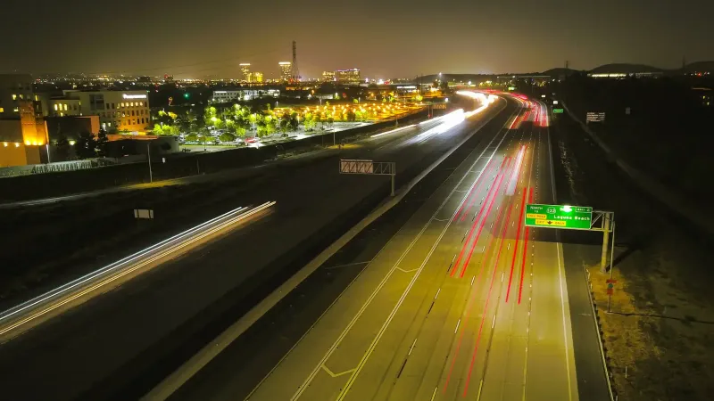 A captivating time-lapse of highway traffic light trails at night in an urban cityscape.