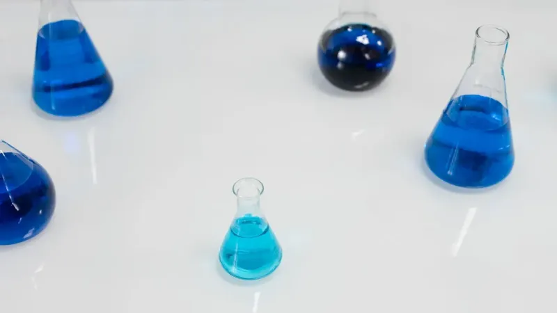 Various glass flasks filled with blue liquid in a scientific setting, perfect for research themes.