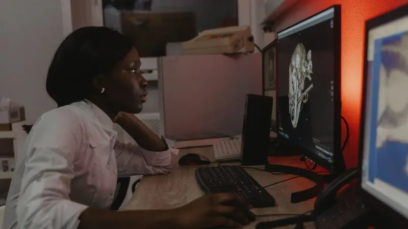 Veterinarian analyzing a 3D skull scan on dual monitors in an office setting.