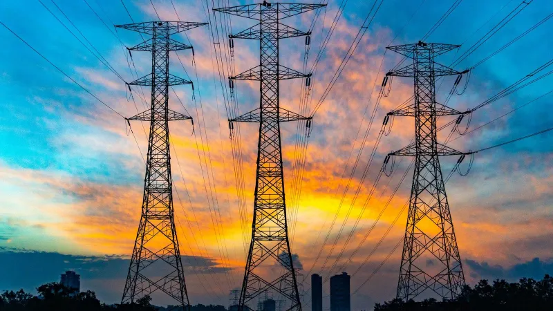 High voltage power lines against a dramatic sunset sky, symbolizing energy and technology.