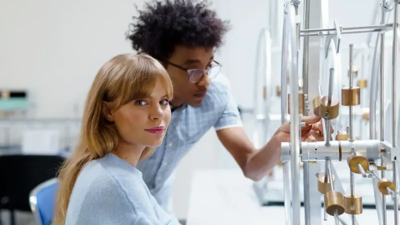 University students exploring physics concepts in a laboratory setting with experimental equipment.