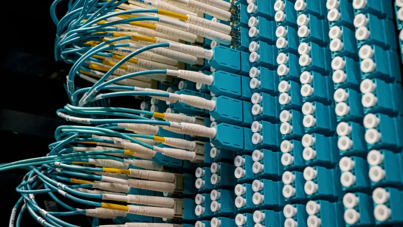 Detailed view of fiber optic patch cables connecting to a blue patch panel in a data center.