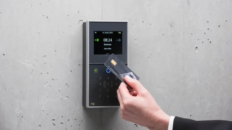 A businessman uses a secure card reader access system against a concrete wall.