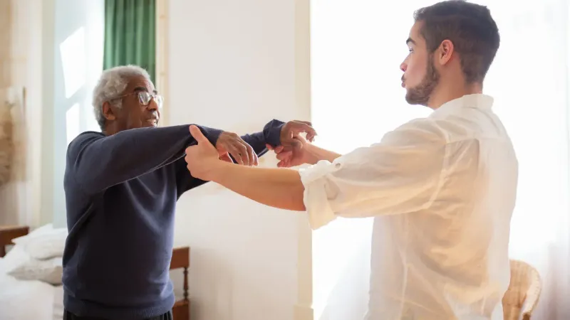 Senior recibiendo apoyo del cuidador en el hogar, mostrando atención y comunicación.