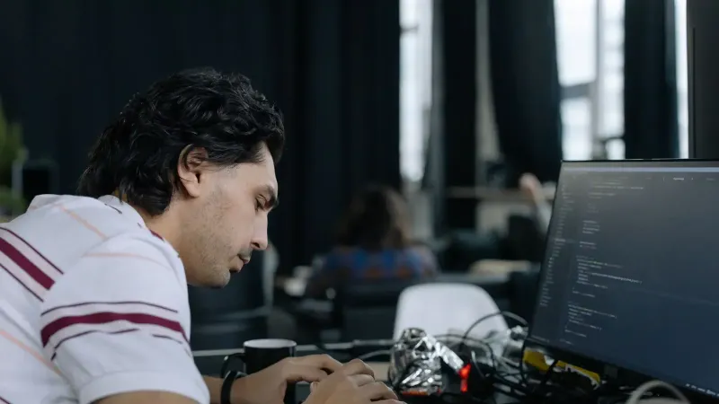 A coder intensely typing at a workstation in a contemporary office setup.