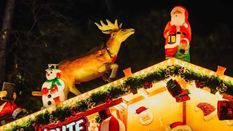 Exhibición navideña vibrante con Papá Noel, un muñeco de nieve y un reno en una azotea decorada.