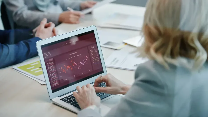 Profesionales de negocios que analizan los datos del mercado de valores en una computadora portátil durante una reunión.