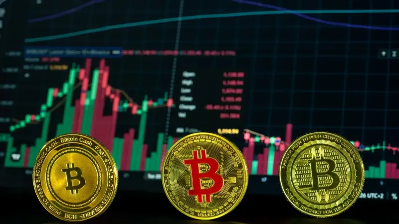 Close-up of bitcoin coins in front of a financial market graph, symbolizing digital investment trends.