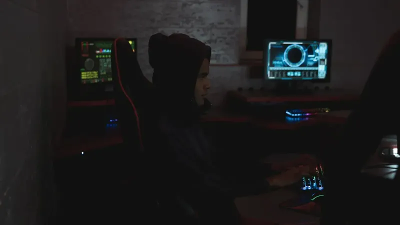Un profesional que analiza datos en múltiples monitores en un cuarto oscuro, destacando los temas de ciberseguridad.