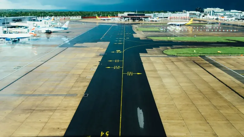 Vista aérea de una pista de aeropuerto con varios aviones estacionados en un día nublado. Ideal para temas de viajes y aviación.