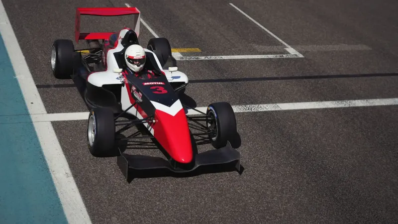 Imagen dinámica de un coche de carreras en una pista en Abu Dhabi, mostrando velocidad y precisión.