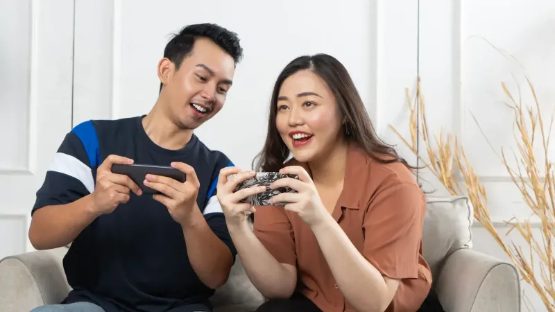 Pareja joven disfrutando de juegos en smartphones en interiores, capturando alegría y unión.