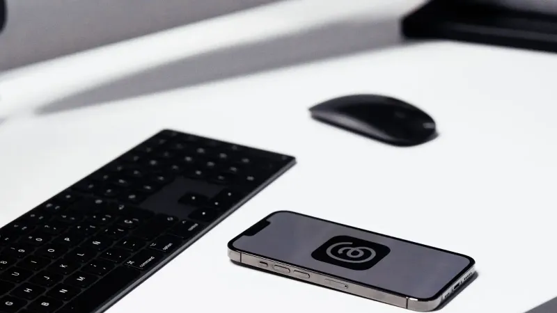 Un elegante espacio de trabajo con un teléfono inteligente, teclado y mouse en un escritorio blanco limpio.