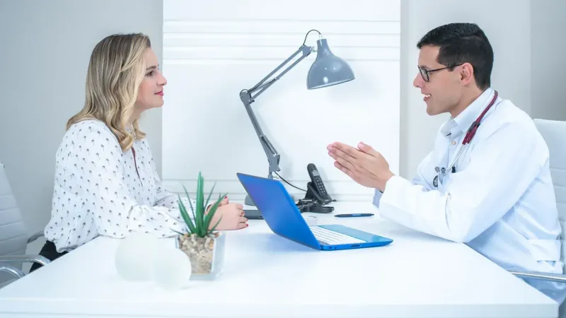 Un médico realiza una consulta al paciente en un consultorio médico moderno y brillante.