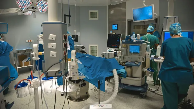 Un moderno quirófano con personal médico realizando cirugía, equipado con instrumentos de alta tecnología.