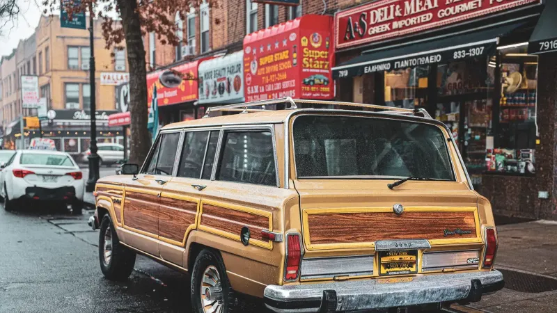 Classic Vintage Wagoneer estacionado en una bulliciosa calle de la ciudad con escaparates y ambiente urbano.