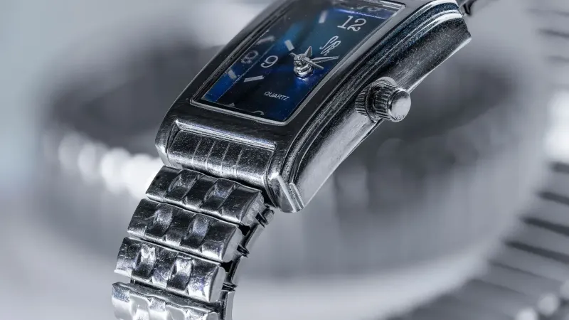 Imagen detallada de un clásico reloj de pulsera de cuarzo plateado que muestra su esfera azul y pulsera de metal.
