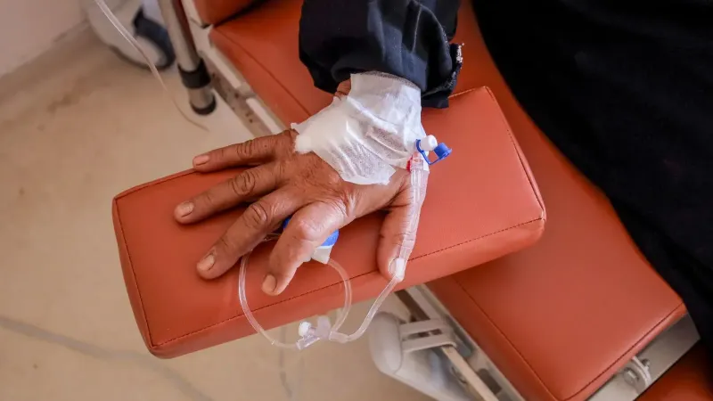 Close-up of a patient's hand receiving chemotherapy treatment in a medical facility.