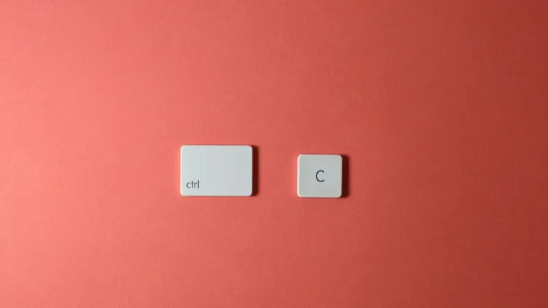 Teclas simples de teclado Ctrl y C sobre un fondo coral, que representa la función de copia.