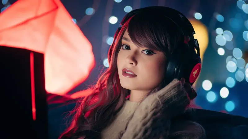 Una mujer con auriculares posa en el interior con un ambiente acogedor, ideal para temas de juego.