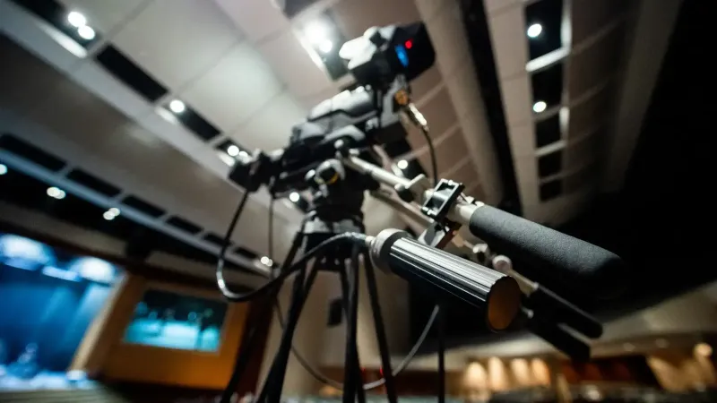 From below of modern professional video camera with wires placed on tripod in studio on blurred background