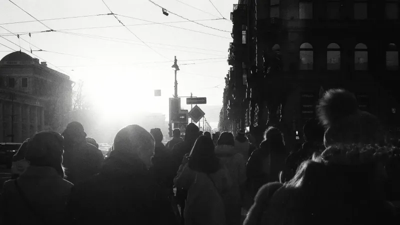 Silhouettes of people walking in a city street during sunrise with a vintage, moody tone.