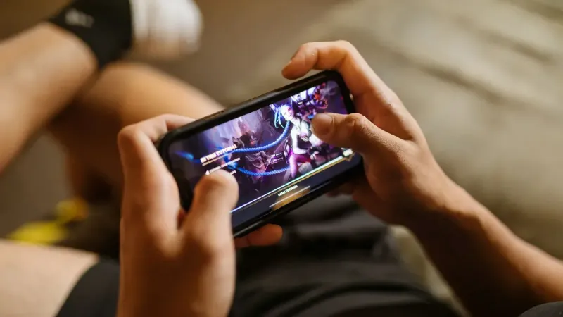 Una persona que juega un videojuego móvil en un teléfono inteligente, centrándose en el estilo de vida de los juegos y la tecnología.