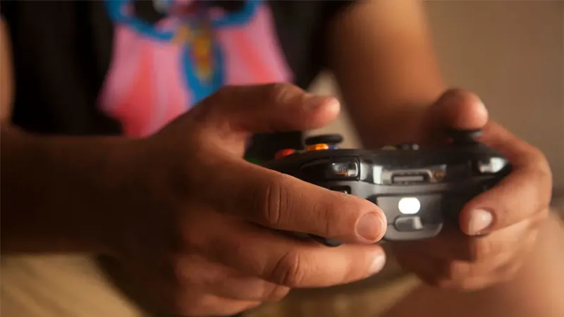 Una persona que sostiene un controlador de juego inalámbrico en el interior, enfatizando los juegos relajados.