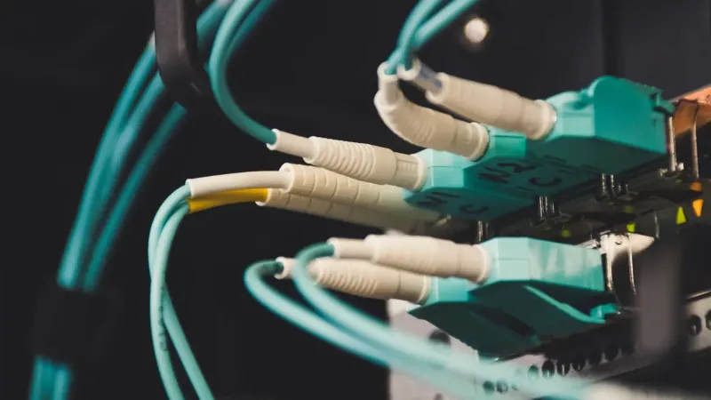 Vista detallada de cables y puertos de fibra óptica en una sala de servidores, mostrando conectividad.