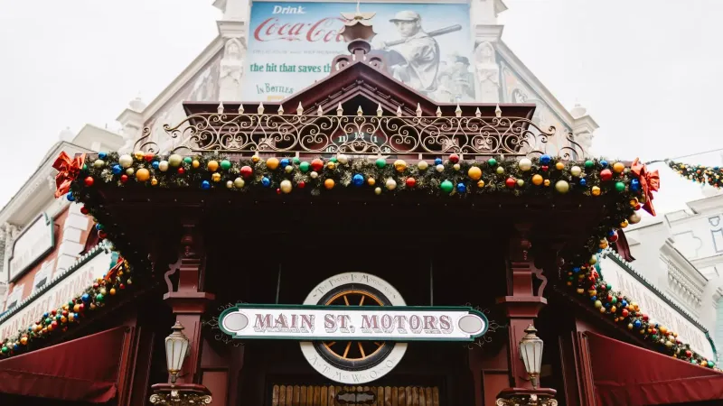 A festive view of 'Main St. Motors' adorned with colorful baubles and holiday decor in Paris, France.