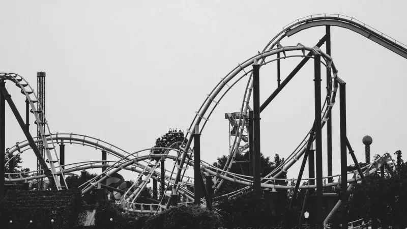 Imagen monocromática de una montaña rusa con pistas en bucle en un parque de atracciones al aire libre.