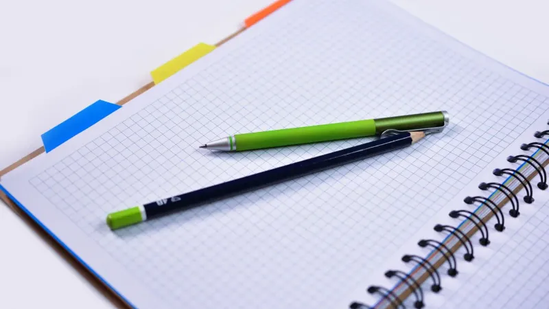 Open spiral notebook with graphing paper, pen, and pencil, ideal for notes or sketches.