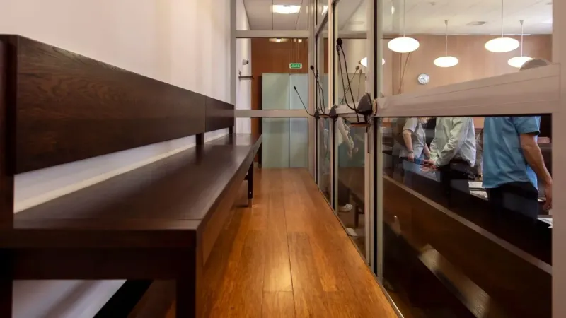 Interior view of a courtroom in Wrocław, Poland, featuring wooden benches and glass partitions.