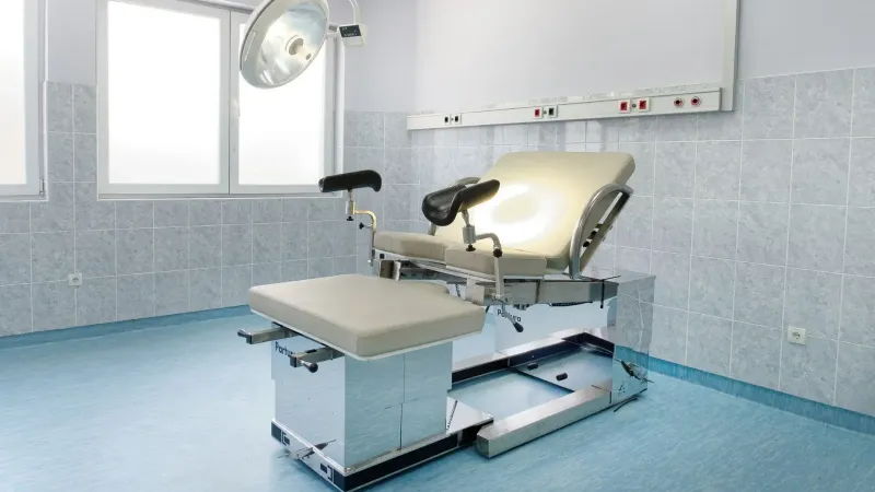 Sala de examen ginecológica brillante con silla ajustable y luz de techo en un centro médico.