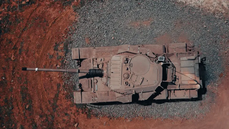 Aerial shot of a military tank parked on rugged terrain captured by drone.