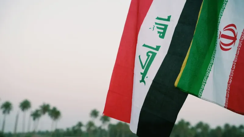 Iraqi and Iranian flags waving with palm trees in the background, Karbala, Iraq.