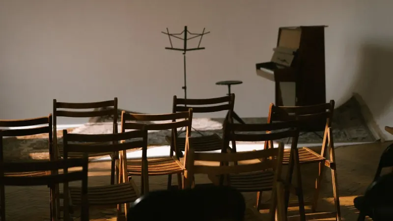 Una sala de música vacía con sillas de madera, un piano y un partitura listo para una actuación.