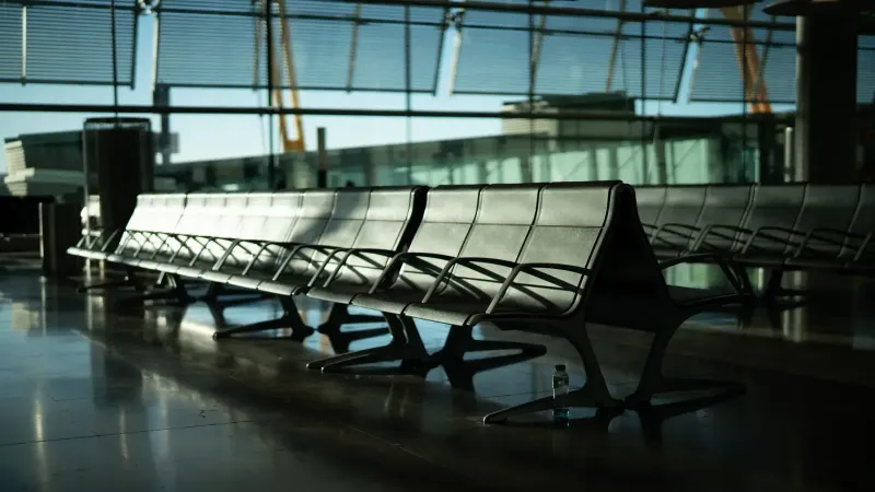 Zona de estar desierta en el aeropuerto con luz solar que fluye a través de grandes ventanas. Ambiente tranquilo y silencioso.