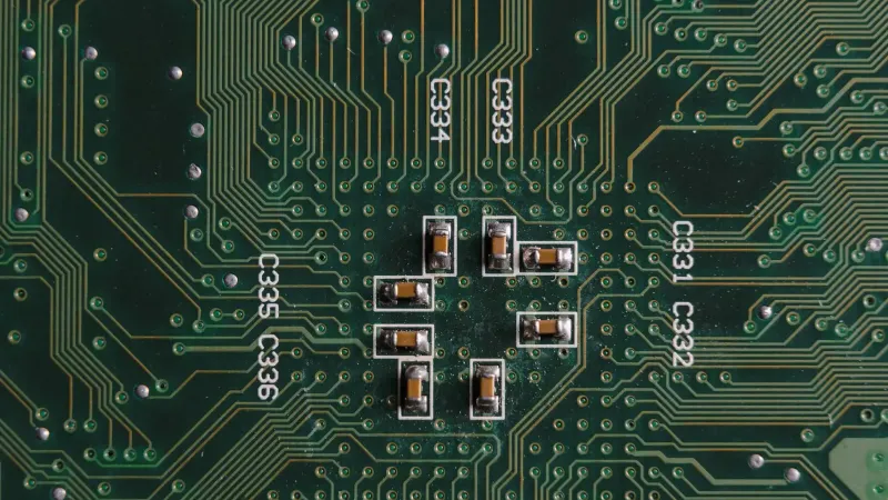 Explore el intrincado diseño y los componentes en una placa de circuito verde con condensadores y vías.