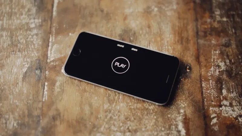 Close-up de un smartphone en una mesa de madera mostrando un icono de juego en su pantalla.