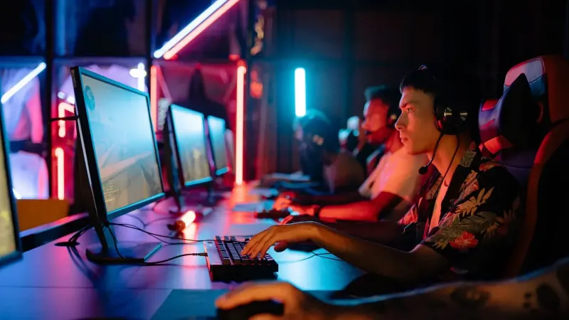 Group of gamers immersed in competitive esports at a cyber arena with neon lighting.