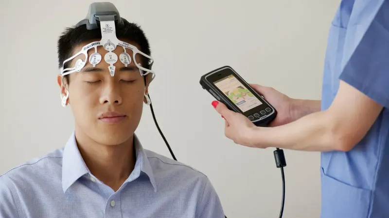 Profesional de la salud que realiza un examen de EEG utilizando un dispositivo BrainScope en un paciente masculino.
