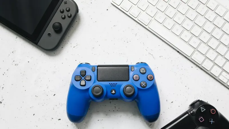 Vista superior de varios controladores de juegos y un teclado en una superficie blanca.
