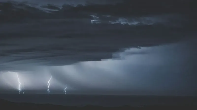 Peligrosos relámpagos brillantes en el cielo nublado y sombrío sobre el agua interminable del océano en la noche
