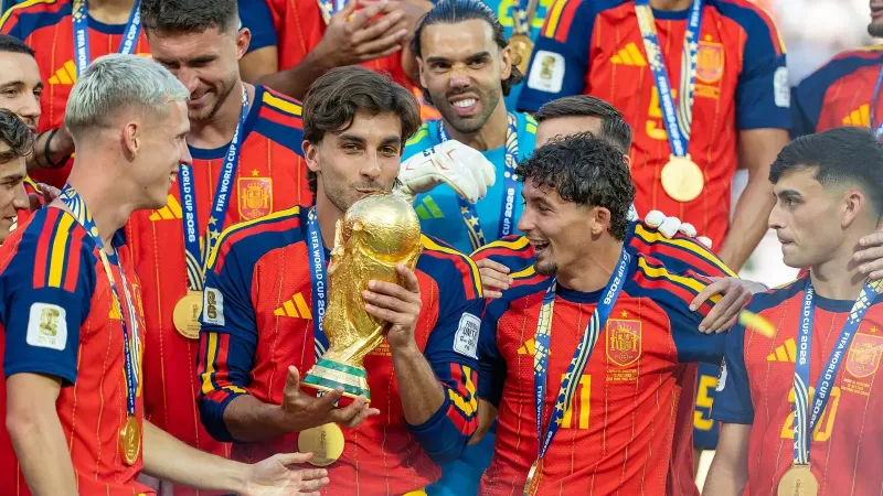 Ferran Torres besa el trofeo de la Copa del Mundo rodeado de compañeros de la selección española con sus medallas al cuello