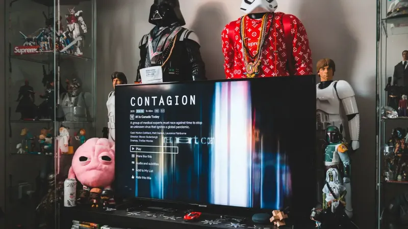 Desktop computer with creative video game on screen near assorted toy superheros on glass shelves in modern style apartment
