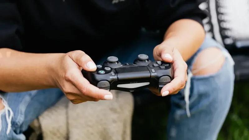 Close-up de manos sosteniendo un controlador de videojuego, mostrando ocio y juegos en interiores.