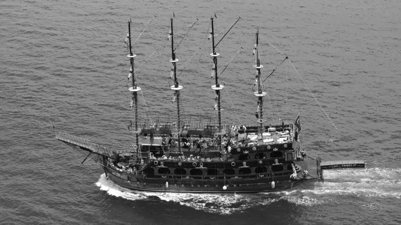 Foto aérea en blanco y negro de un barco pirata navegando el océano, mostrando la aventura náutica.